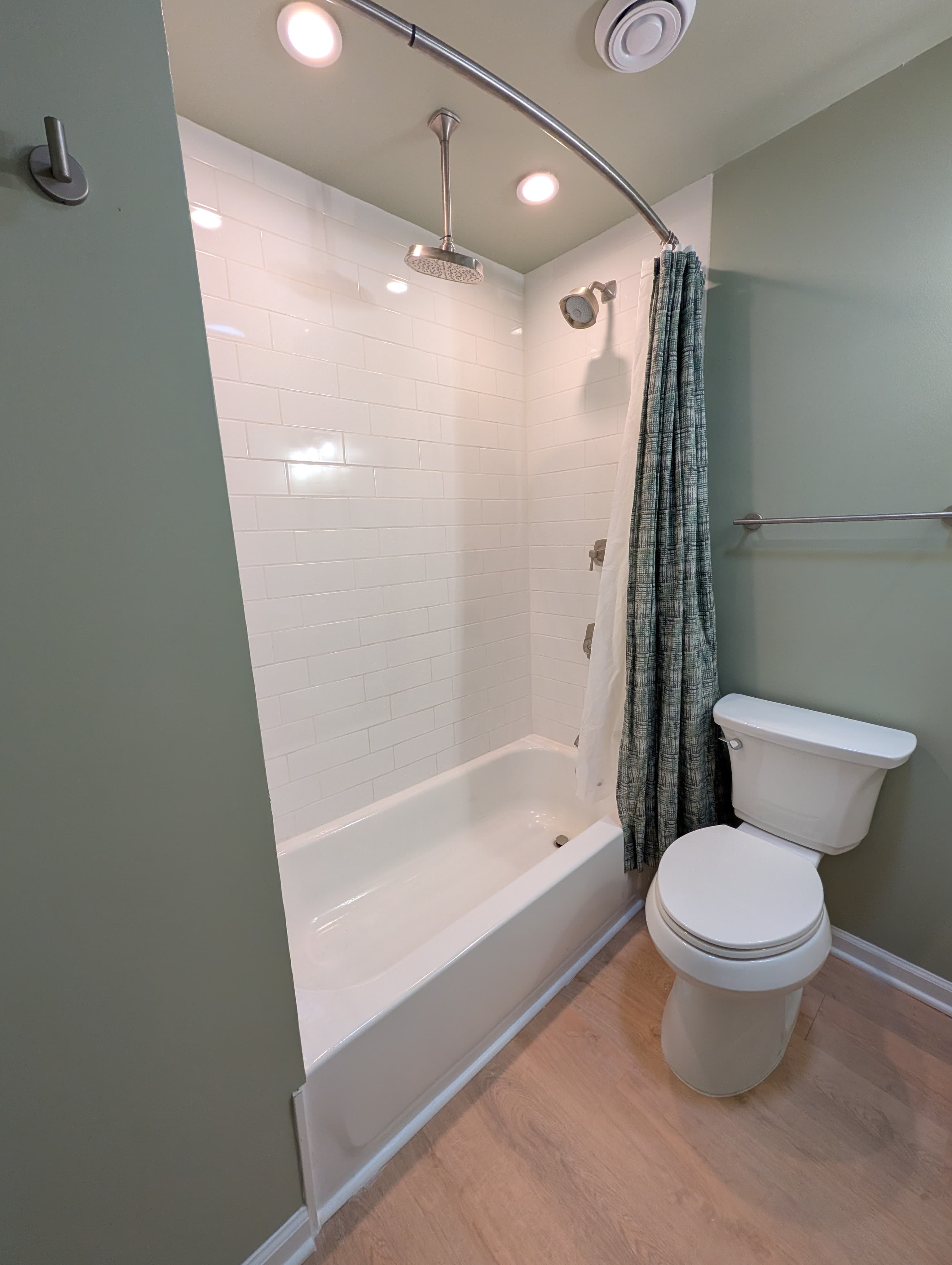 Retiled tub and shower surround with subway tile, curved shower rod, and rainfall showerhead