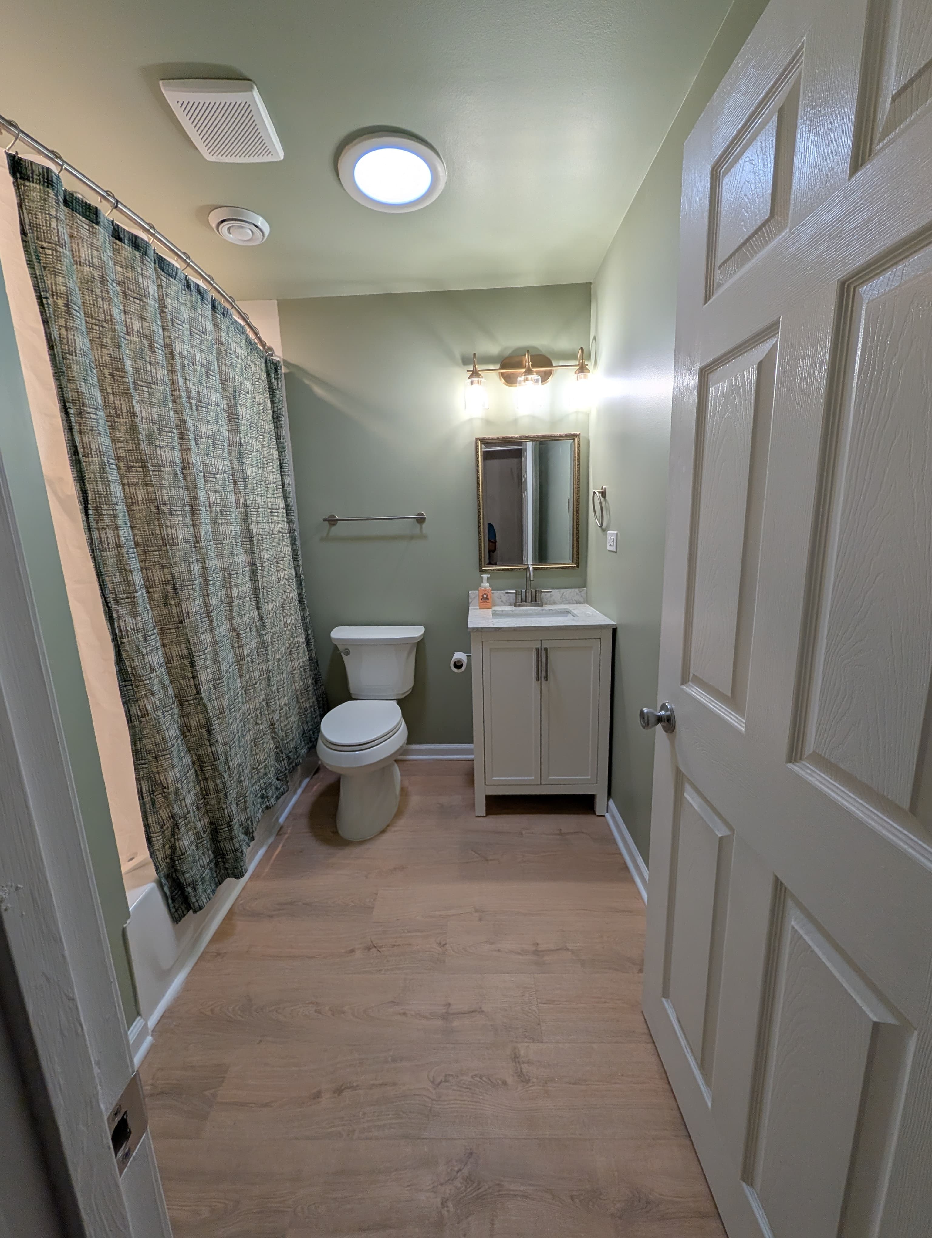 Remodeled bathroom with new vanity, mirror, lighting, and flooring